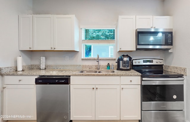 kitchen featuring light stone counters, white cabinetry, sink, and stainless steel appliances