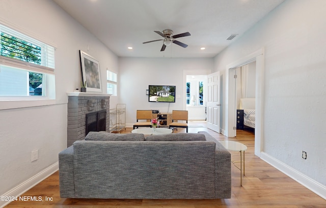 living room featuring wood-type flooring, a fireplace, and ceiling fan