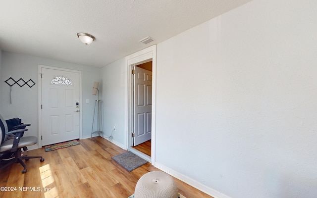 entryway with a textured ceiling and light hardwood / wood-style flooring