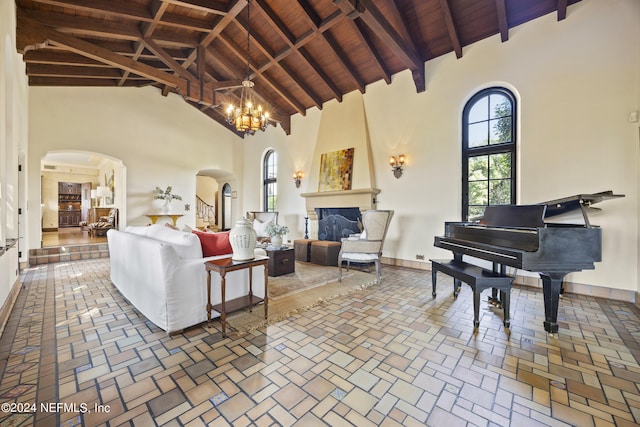 living room with beamed ceiling, a chandelier, high vaulted ceiling, and a fireplace