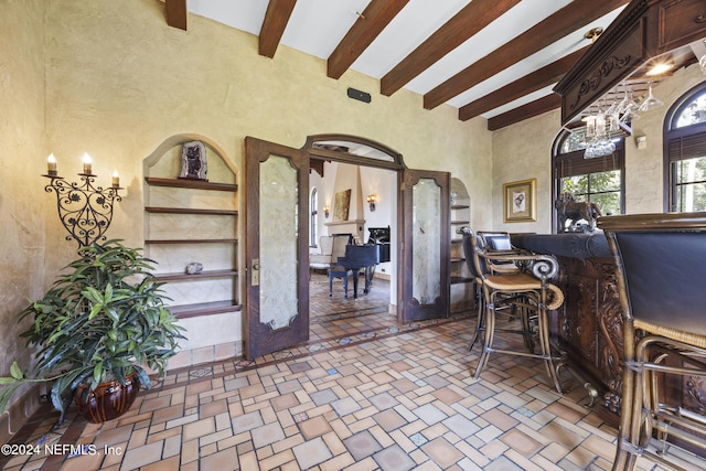 entrance foyer featuring beam ceiling, a fireplace, and an inviting chandelier