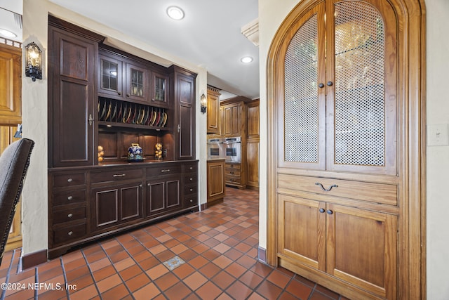 kitchen featuring dark tile patterned flooring, dark brown cabinets, and oven