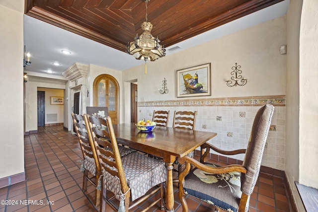 dining room with crown molding, dark tile patterned floors, wooden ceiling, and tile walls