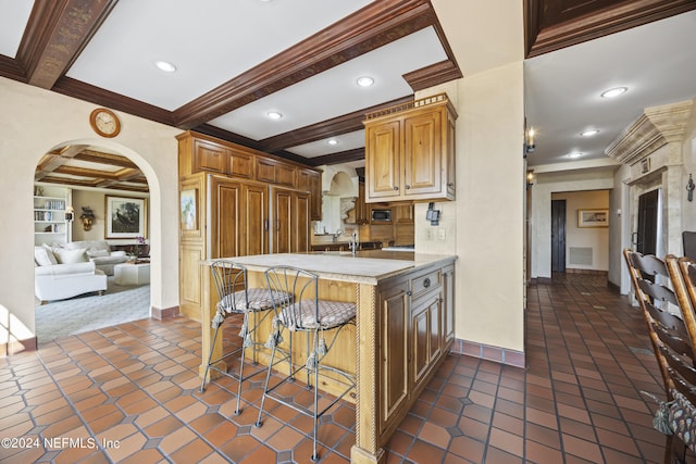 kitchen with kitchen peninsula, beamed ceiling, a kitchen bar, and crown molding