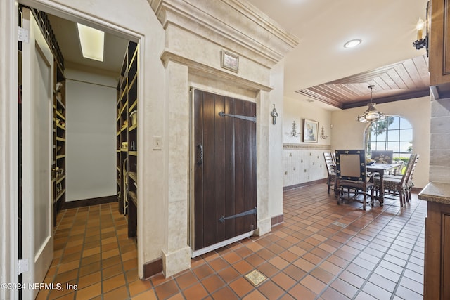 kitchen with crown molding, dark tile patterned floors, and a notable chandelier