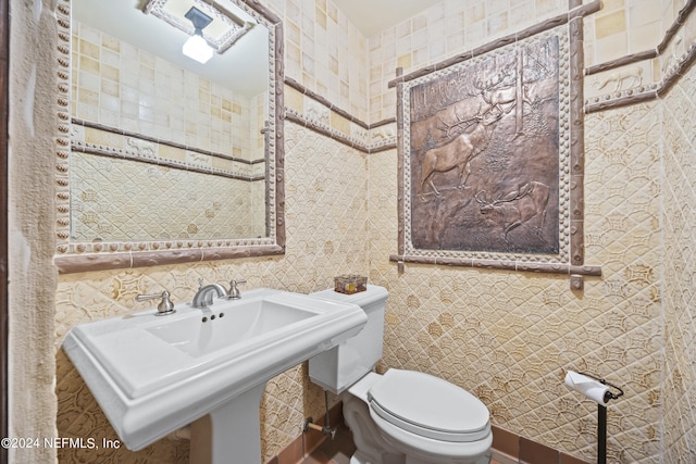 bathroom featuring toilet, sink, and tile walls