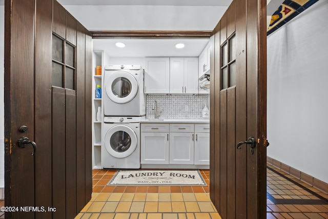 washroom featuring cabinets, light tile patterned flooring, and stacked washer and clothes dryer