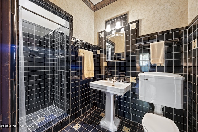 bathroom with a tile shower, toilet, tile patterned floors, and tile walls