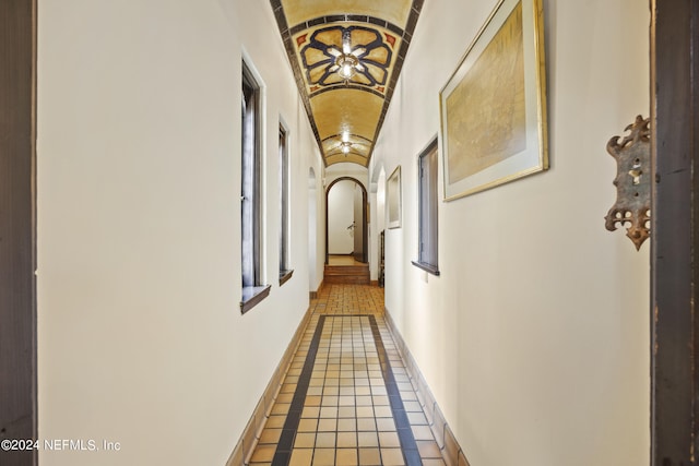 corridor featuring vaulted ceiling and tile patterned flooring