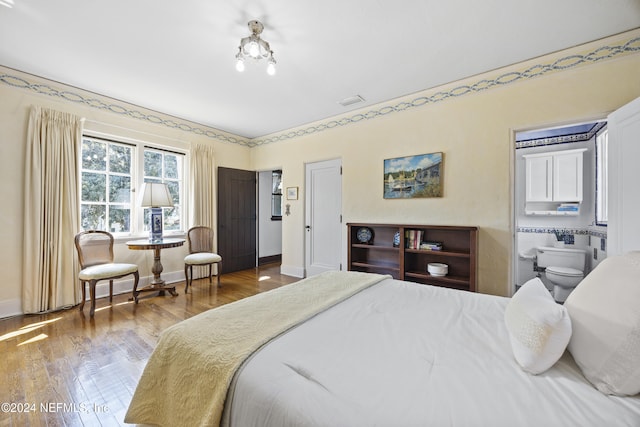 bedroom with ensuite bath and hardwood / wood-style flooring