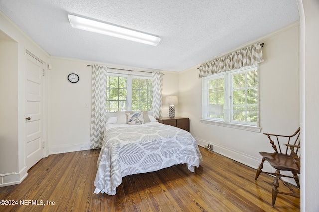 bedroom featuring dark wood-type flooring, ornamental molding, and a textured ceiling