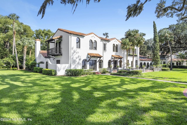 mediterranean / spanish house featuring a front yard and a balcony