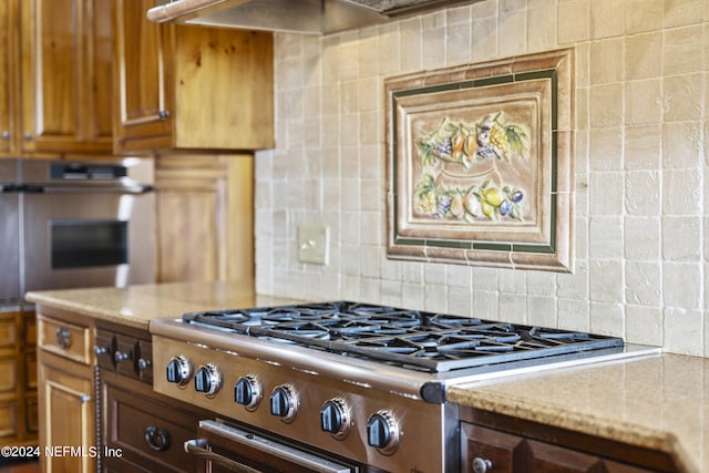 kitchen featuring light stone countertops, stainless steel appliances, and backsplash