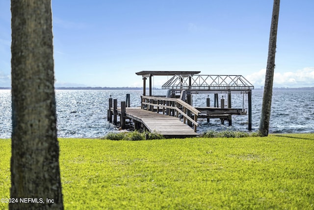 view of dock with a yard and a water view