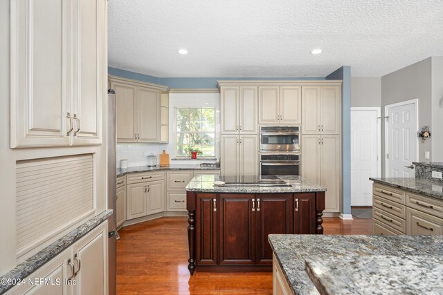 13601 Emerald Cove Ct, Jacksonville, FL 32225 - kitchen featuring double oven, cream cabinetry, wood finished floors, and a textured ceiling