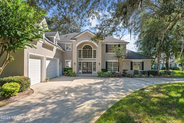 view of front facade with a garage, a shingled roof, concrete driveway, and stucco siding