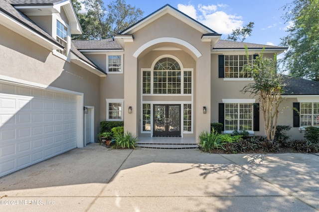 13601 Emerald Cove Ct, Jacksonville, FL 32225 - view of exterior entry with french doors, concrete driveway, an attached garage, a shingled roof, and stucco siding