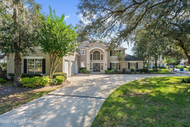 13601 Emerald Cove Ct, Jacksonville, FL 32225 - traditional-style house with concrete driveway, a front lawn, french doors, a garage, and stucco siding