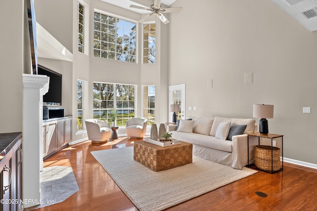 13601 Emerald Cove Ct, Jacksonville, FL 32225 - living room featuring visible vents, wood finished floors, a healthy amount of sunlight, and a high ceiling