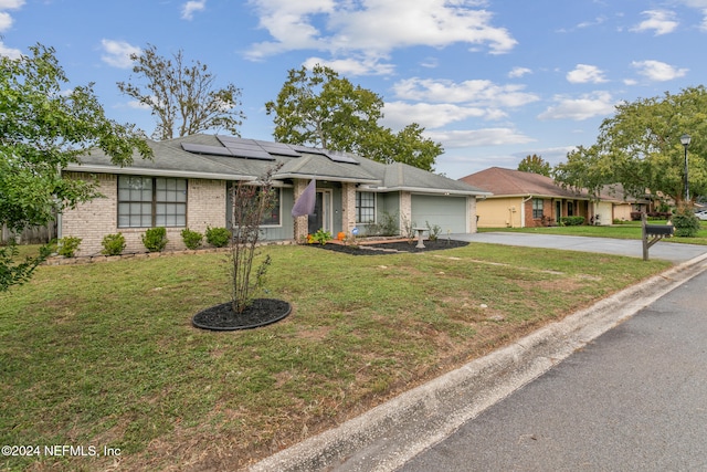 single story home with solar panels, a front yard, and a garage