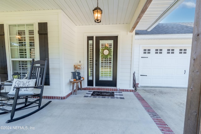 view of exterior entry with a garage and a porch