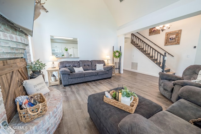 living room featuring wood-type flooring, high vaulted ceiling, and a chandelier