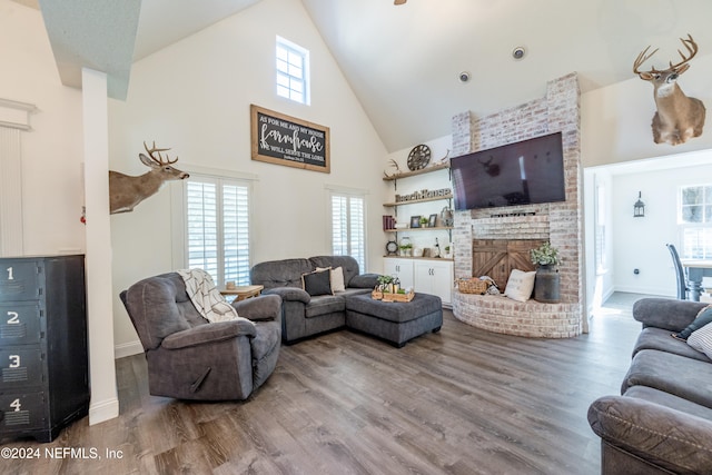 living room featuring a brick fireplace, high vaulted ceiling, and hardwood / wood-style floors