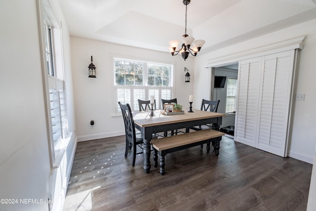 dining area featuring a chandelier, dark hardwood / wood-style flooring, and a tray ceiling