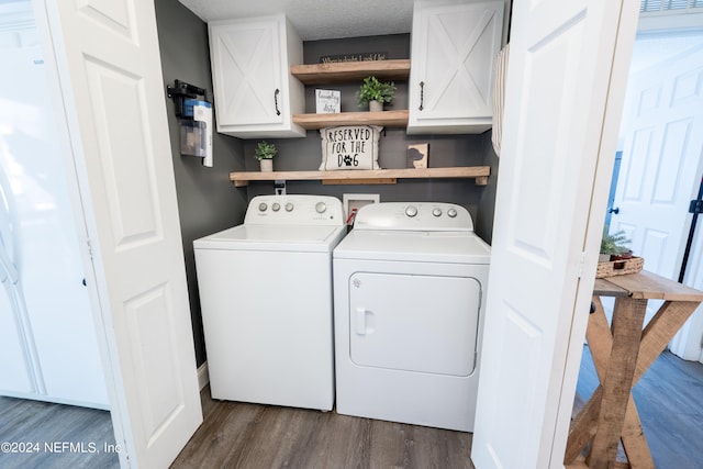 clothes washing area featuring a textured ceiling, washer and dryer, cabinets, and dark hardwood / wood-style flooring