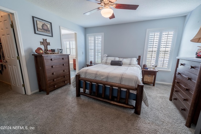 carpeted bedroom with ceiling fan and a textured ceiling