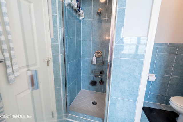 bathroom with walk in shower, toilet, and tile walls