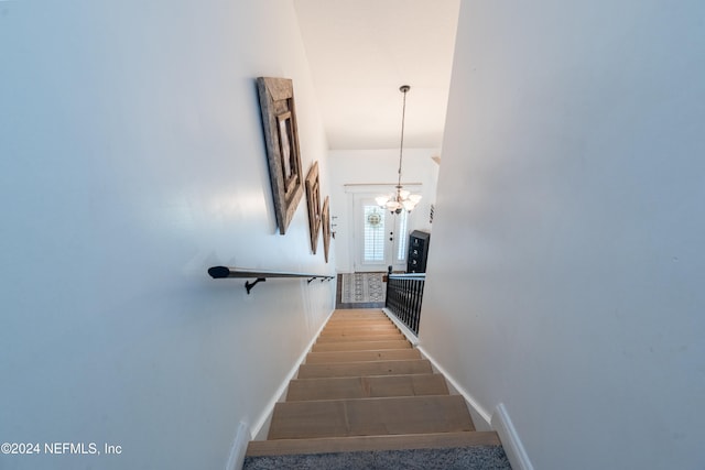 staircase featuring hardwood / wood-style floors and a notable chandelier