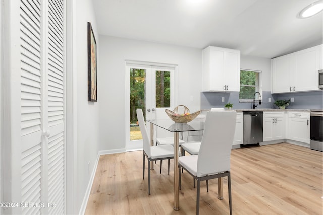 kitchen with appliances with stainless steel finishes, white cabinetry, sink, and light hardwood / wood-style floors