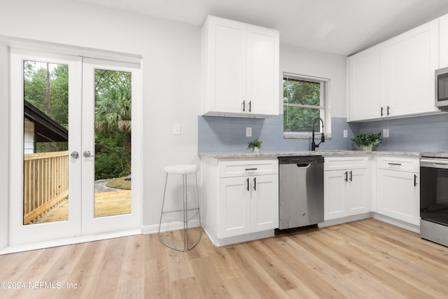 kitchen with appliances with stainless steel finishes, light hardwood / wood-style flooring, a wealth of natural light, and white cabinetry