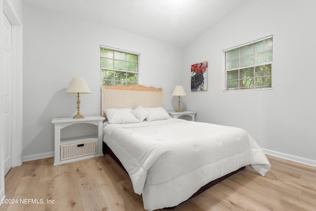 bedroom with light wood-type flooring and lofted ceiling