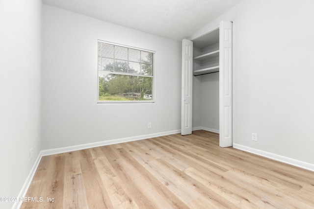 unfurnished bedroom with a closet, light hardwood / wood-style floors, and a textured ceiling