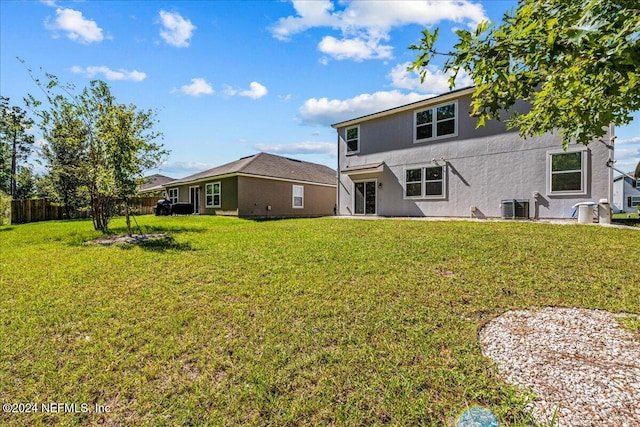 rear view of property featuring a yard and central AC unit