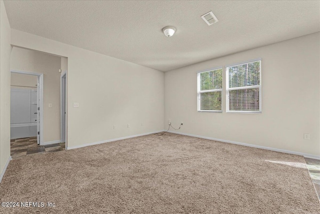 carpeted empty room with a textured ceiling