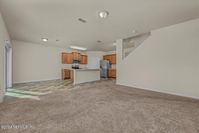 unfurnished living room with light colored carpet and a textured ceiling