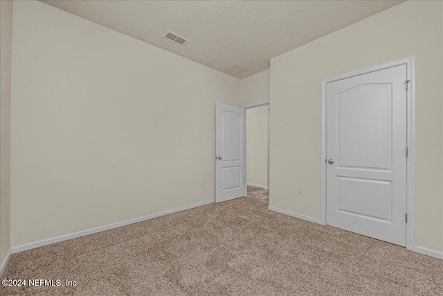 unfurnished bedroom with a textured ceiling and light colored carpet