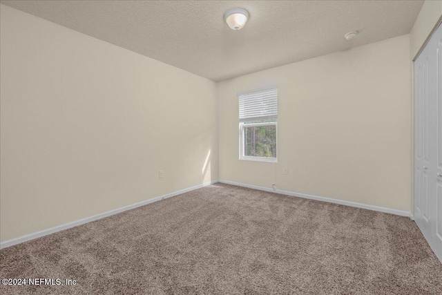 carpeted empty room with a textured ceiling