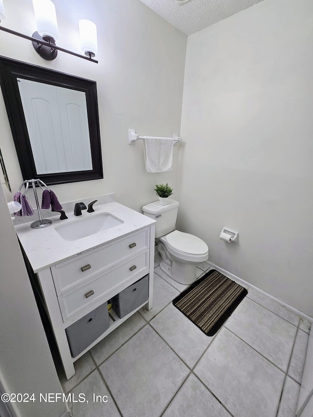 bathroom with vanity, toilet, a textured ceiling, and tile patterned floors