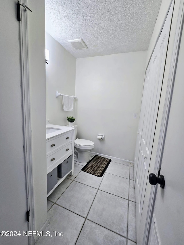 bathroom featuring tile patterned flooring, a textured ceiling, vanity, and toilet