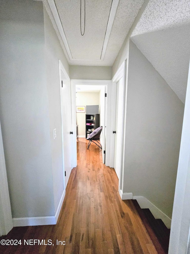 hallway with wood-type flooring and a textured ceiling