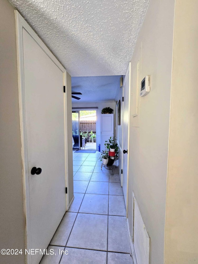 hallway with light tile patterned floors and a textured ceiling