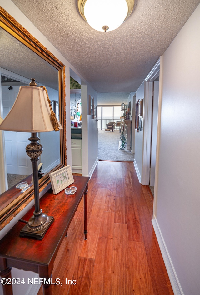 hall with hardwood / wood-style flooring and a textured ceiling