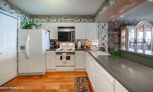 kitchen with white appliances, sink, light wood-type flooring, a textured ceiling, and white cabinets