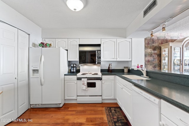 1301 1st St S Unit 1202, Jacksonville Beach, FL 32250 - kitchen with white appliances, dark countertops, white cabinets, a sink, and a textured ceiling