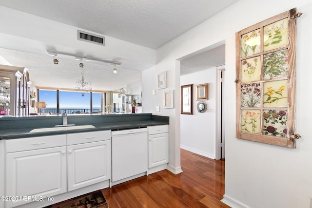 1301 1st St S Unit 1202, Jacksonville Beach, FL 32250 - kitchen with white dishwasher, a sink, dark wood finished floors, dark countertops, and white cabinets