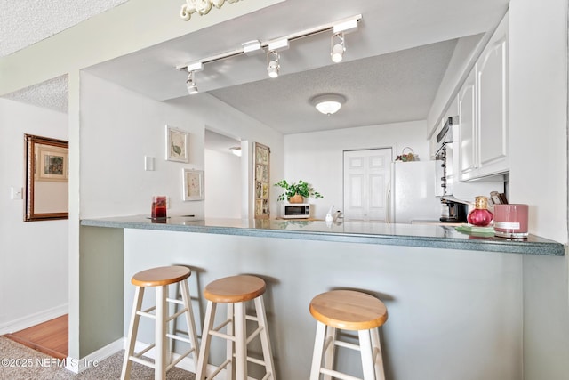 1301 1st St S Unit 1202, Jacksonville Beach, FL 32250 - kitchen featuring white appliances, a peninsula, a textured ceiling, white cabinets, and track lighting